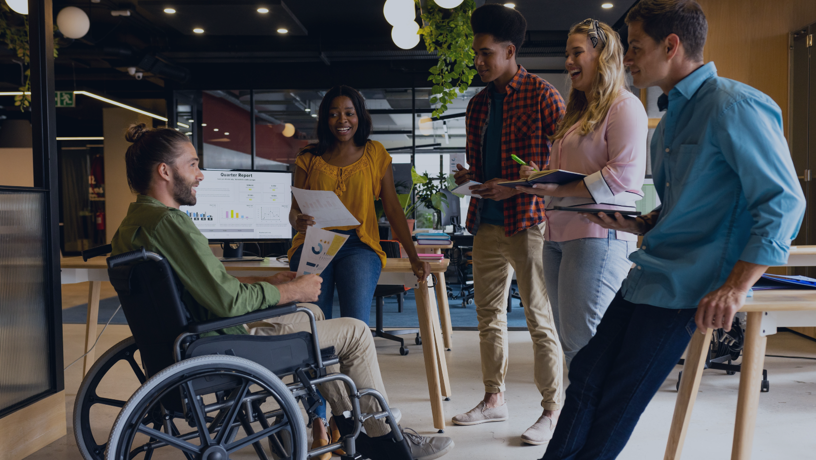 A diverse team of professionals engaged in a collaborative discussion in a modern office, including a man in a wheelchair contributing to the conversation, symbolizing inclusivity, teamwork, and people and culture transformation.