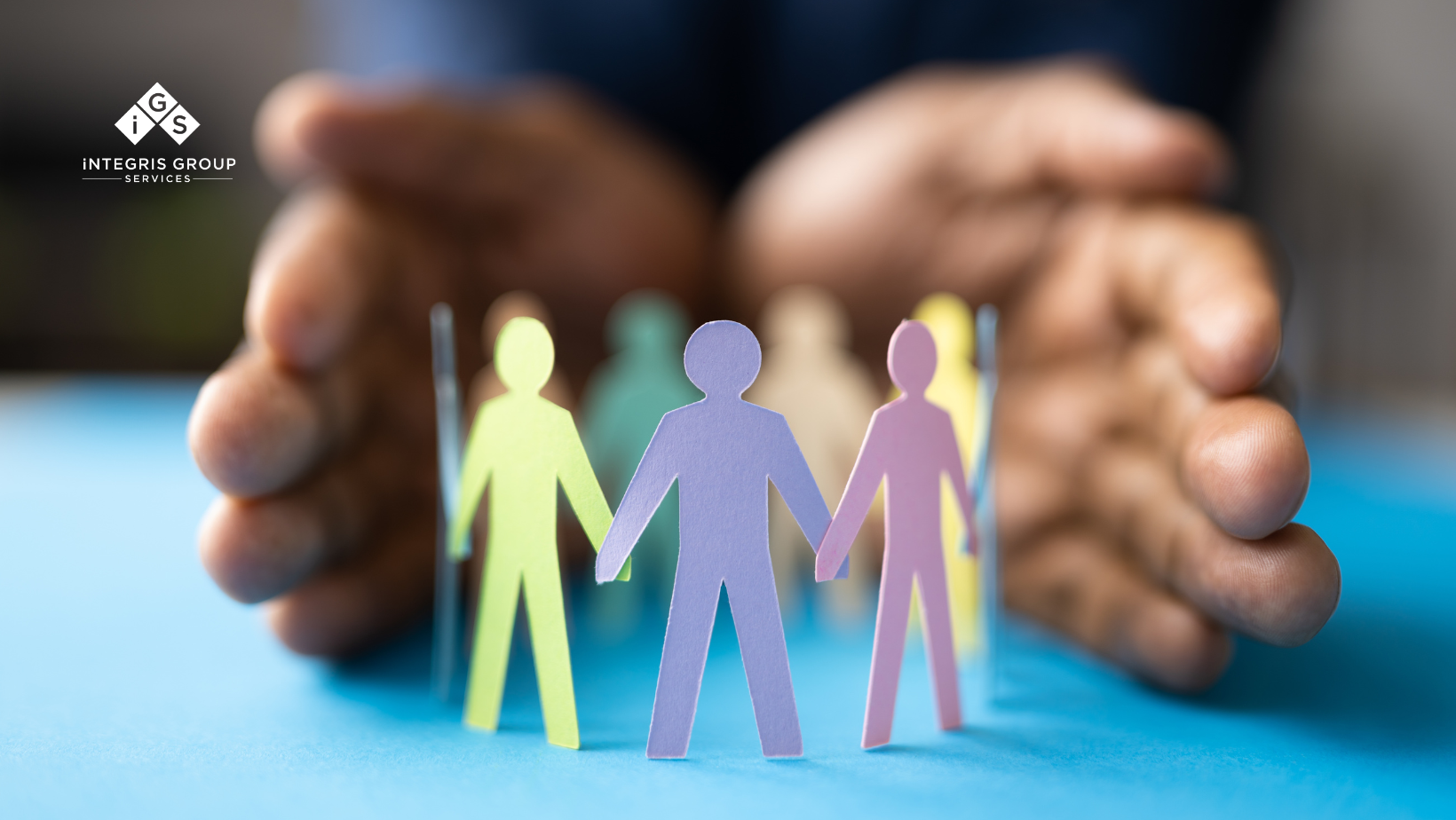 A close-up of hands gently surrounding a circle of colorful paper cutouts representing diverse individuals, symbolizing inclusivity, workplace culture, and people and culture transformation.