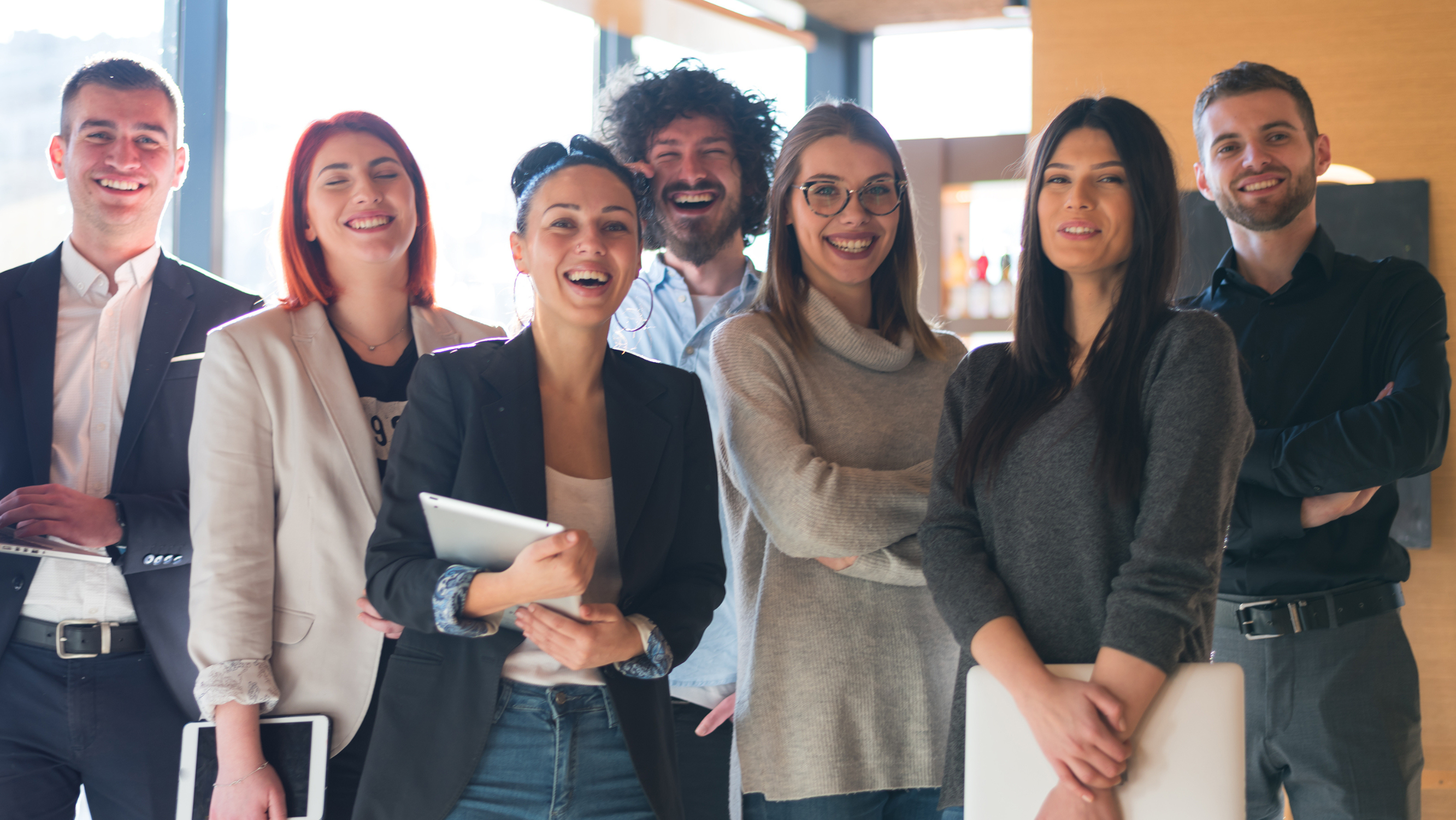 A diverse group of happy professionals in a bright office, reflecting a supportive, People-First Organisation.