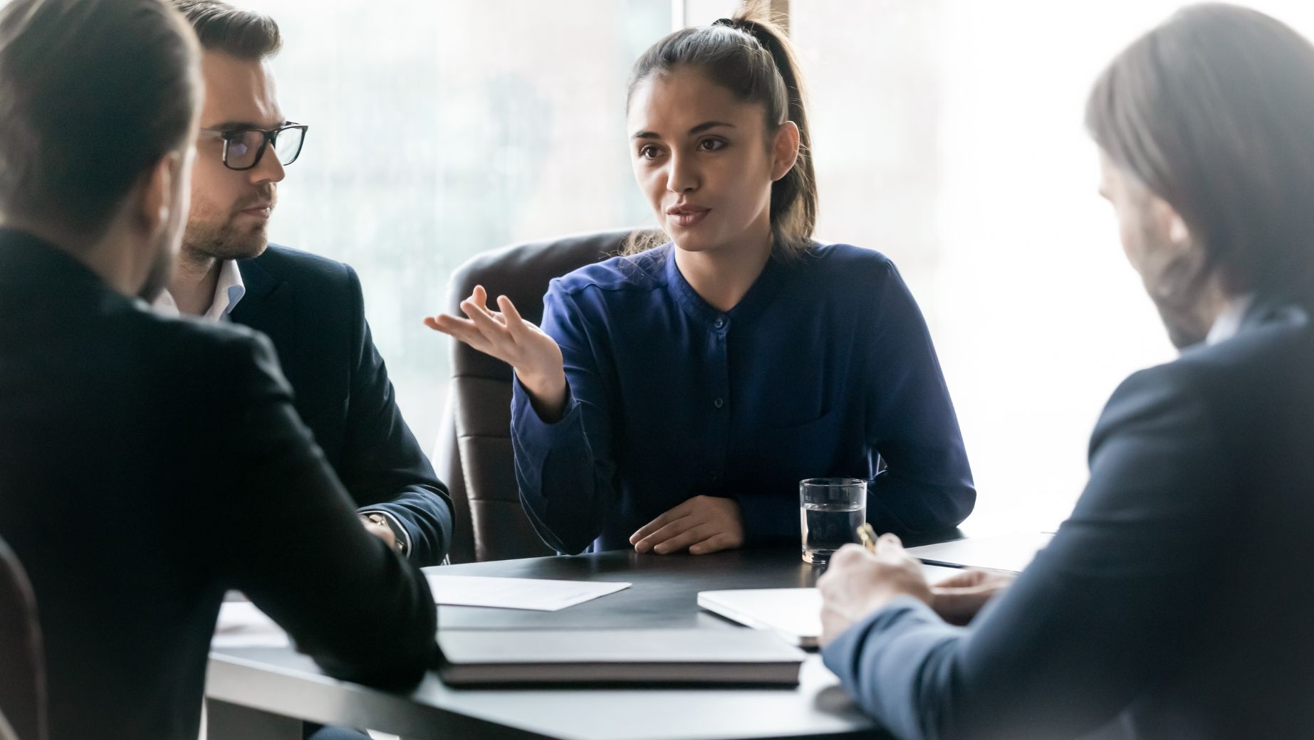 Professional woman addressing a group during a serious discussion, symbolizing collaborative problem-solving and reinforcing workplace boundaries.