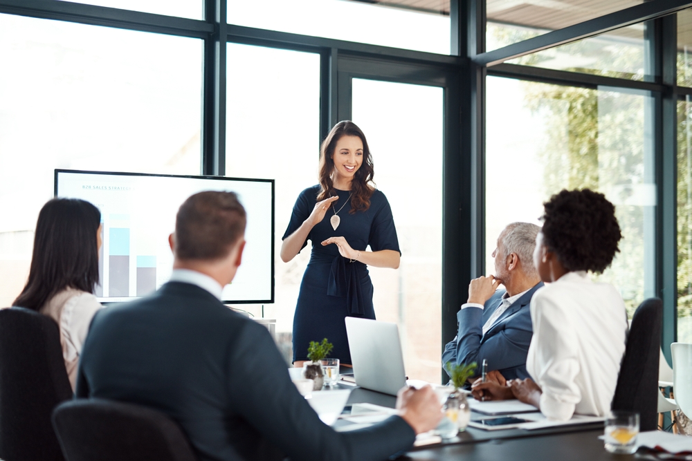 A confident leader engaging with her team during a presentation, exemplifying empathy in leadership through active listening and clear communication in Integris Group Services.