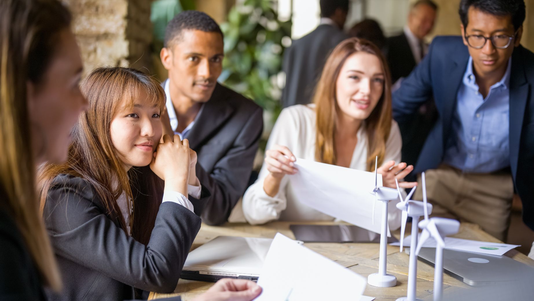 A diverse group of professionals applauding during a successful client collaboration meeting in a modern office.