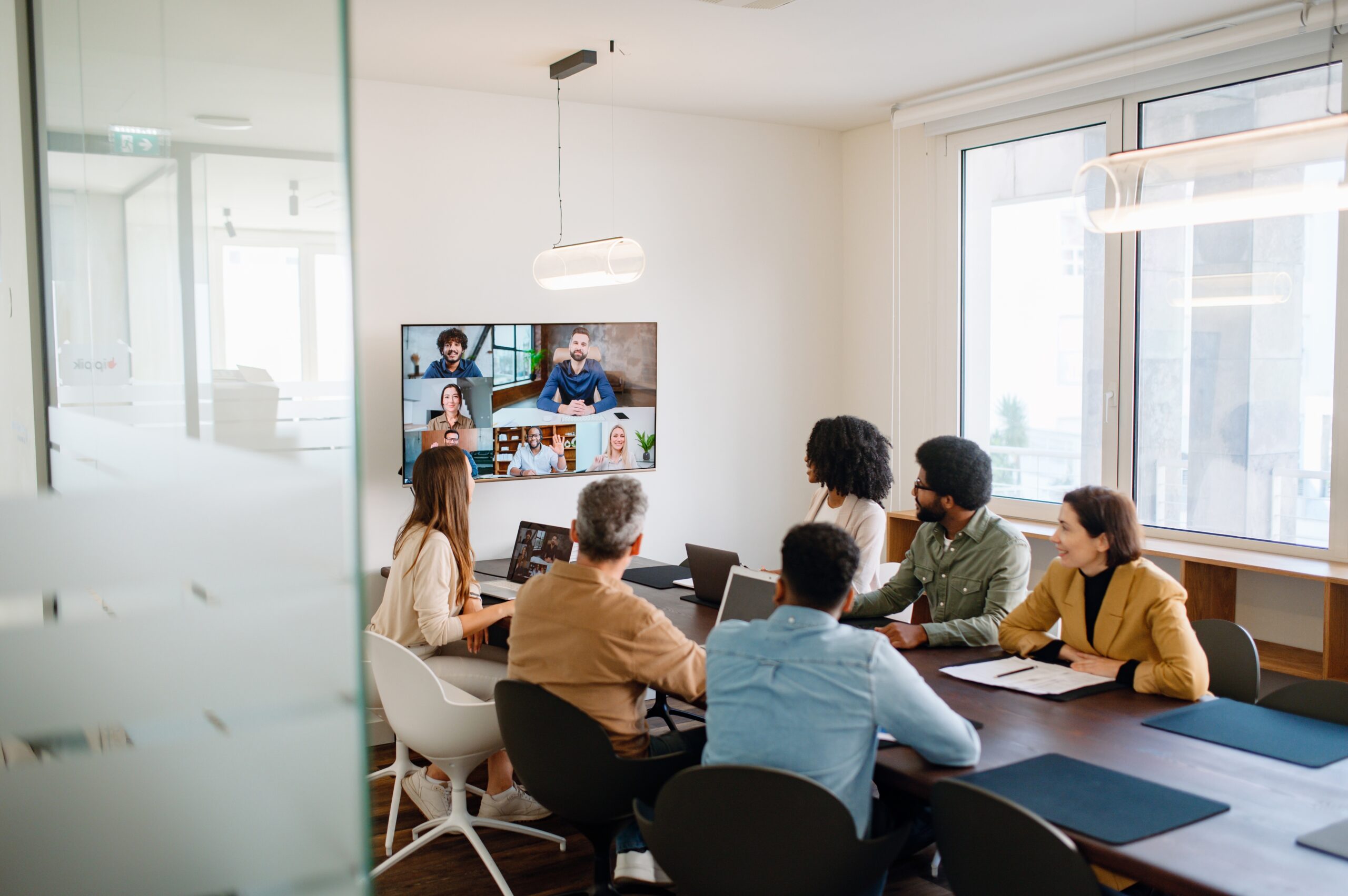 Hybrid meeting in a modern workplace with a mix of in-person and remote team members collaborating.